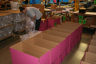 Worker adding products to shipping boxes